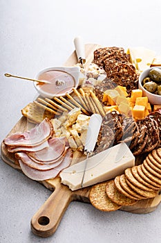 Charcuterie board or cheese and snacks board with honey and olives