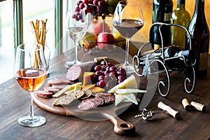 A charcuterie board of gourmet meats and cheese with red, white and rose wine.