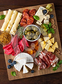 Charcuterie board with a variety of cheeses, salami, chorizzo, prosciutto, honey, grapes, nuts, olives, bread, blueberries