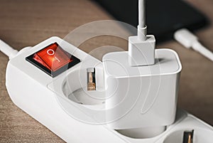 A charger adapter with a USB cable connected to a power supply with a red switch for charging a smartphone