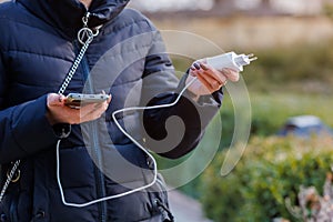 Charger in the female hand of a tourist with a discharged smartphone lifestyle outdoors. Selective focus on charging