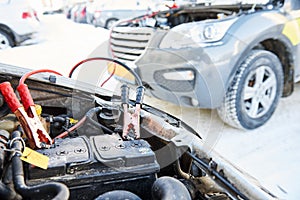 Charging automobile discharged battery by booster jumper cables at winter