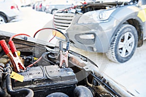 Charging automobile discharged battery by booster jumper cables at winter photo
