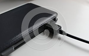 The charging cable is connected to a completely discharged power bank closeup angle view