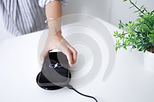 Charging mobile phone battery with wireless charging device in the table. Smartphone charging on a charging pad