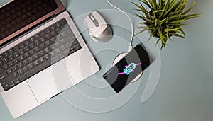 Charging mobile phone battery with wireless charging device on the table.