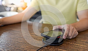 Charging mobile phone battery with wireless device in the table. Smartphone charging on a charging pad. Mobile phone near wireless