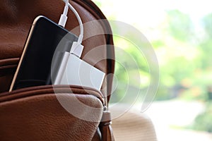 Charging mobile phone with power bank in backpack, closeup. Space for text