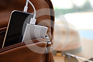 Charging mobile phone with power bank in backpack, closeup. Space for text