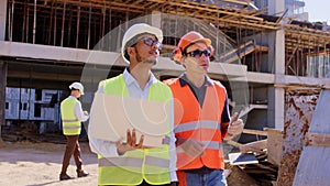 Charismatic Afro American guy engineer walking with a laptop beside the foreman at construction site they analyzing the