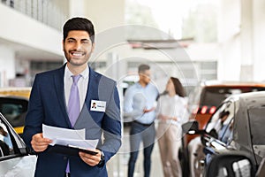 Charismatic arab man sales assistant posing over auto showroom