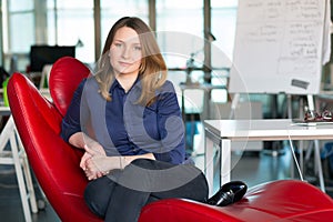 Charismatic Business Person sitting in red Chair at modern Office