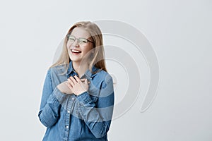 Charismatic and charming young european woman with straight blonde hair wearing stylish spectacles and denim shirt