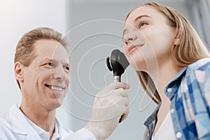 Charismatic doctor exploring teenager skin with dermatoscope in the clinic