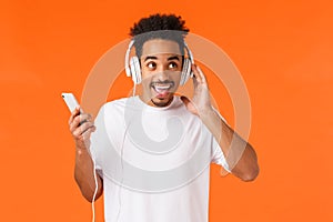 Charismatic excited, happy smiling african-american man with afro haircut, moustache, enjoying music in earphones, touch