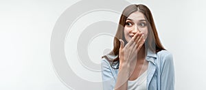 Charismatic girl in casual clothes covers her mouth with her hand.Copy space. Studio shot, white background