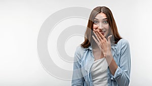 Charismatic girl with long chestnut hair giggling and covers her mouth with her hand. Copy space