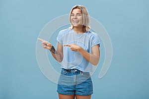 Charismatic joyful attractive athletic woman with fair hair and tanned skin laughing out loud with amusement pointing