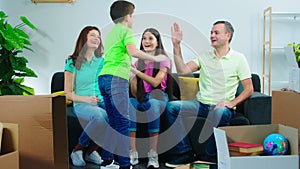 Charismatic kids and their parents in a new house enjoying the moment in the living room while sitting on the sofa