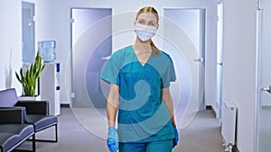 Charismatic lady nurse after the surgery intervention she walking in the corridor hospital with a protective mask in