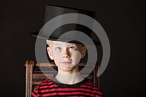 Charismatic little boy wearing an out size top hat