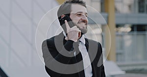 Charismatic man in a suit speaks on his phone in front of business office