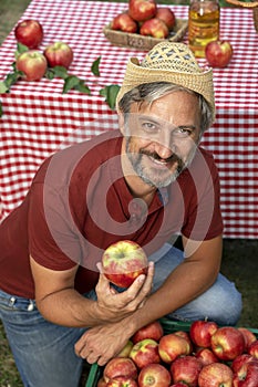 Charismatic Mature Farmer Holding Red Apple and Looking at Camera
