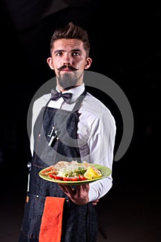 Charismatic waiter helpfully serves appetizing dish in the restaurant.