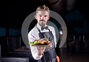 Charismatic waiter serves dish at a festive event.