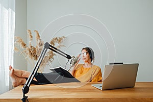 Charismatic woman radio host recording podcast at home studio