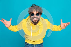 Charismatic young guy with retro sunglasses opening arms and smiling