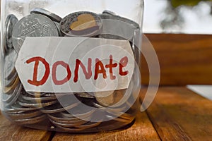 charity box written text of donate and jar in money and small hard,donate written text,wooden table on  donate box