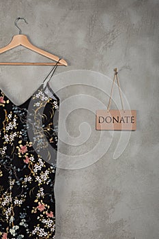 Charity concept - blackboard with text Donate and beautiful dress in floral pattern on a hanger