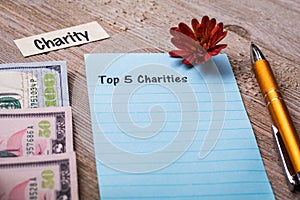 Top 5 Charities concept on notebook and wooden board photo