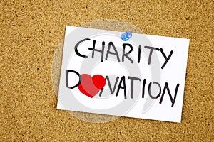 charity donation phrase handwritten on sticky note pinned to a cork notice heart symbol instead of O