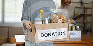 charity, donation and volunteering concept. Volunteer prepare foodstuff box containing food to donate to people poor