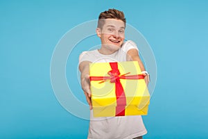 Charity and generosity. Kind happy man in white t-shirt giving gift box to camera and smiling