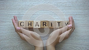 Charity, hands pushing word on wooden cubes, donations and helping in need