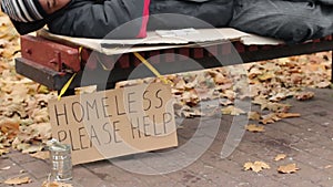 Charity, kind man leaving pack of money on bench while homeless male sleeps