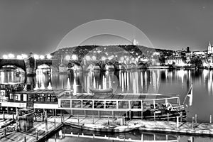 Charles Bridge and the center of Prague on a night black and white HDR photo and with a boat in the foreground