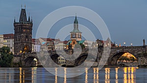 The Charles Bridge day to night timelapse over the Vltava River reflected in water in Prague, Czech Republic