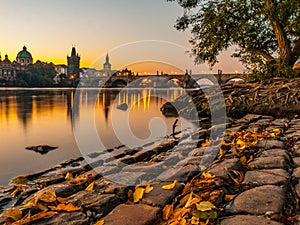 Charles Bridge with Old Town Bridge Tower reflected in Vltava River at morning sunrise time, Prague, Czech Republic