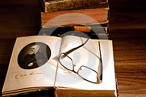 Charles Darwin`s `The origin of species` in front of a pile of 19th century books.