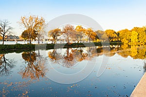 Charles River reflects autumn tones from trees with city buildings in view