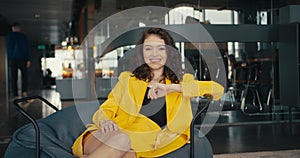 Charm and Confidence: The Art of Professional Posing. A girl in a yellow jacket sits on an armchair in the office and