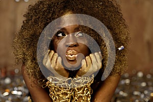 Charming african american model wearing gold accessoaries, makeup and curly hair making kiss lips for camera