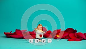 Charming angel and the word love on the background of rose petals .Valentine`s Day. Postcard for the holidays