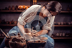 Charming artisan girl demonstrates the process of making ceramic dishes using the old technology. Folk craft.