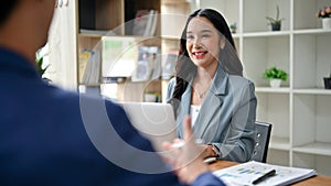 A charming Asian businesswoman is listening to her male colleague explain and share his ideas