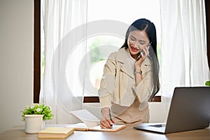 Charming Asian female business employee or secretary talking on the phone